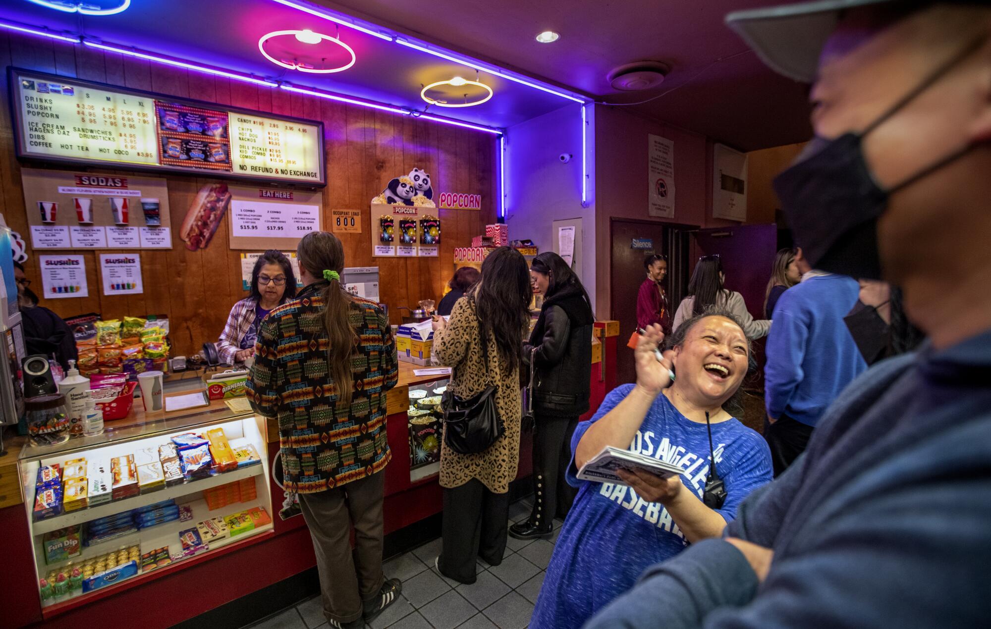Judy Kim laughs as she takes a customer's food order in a movie theatre foyer