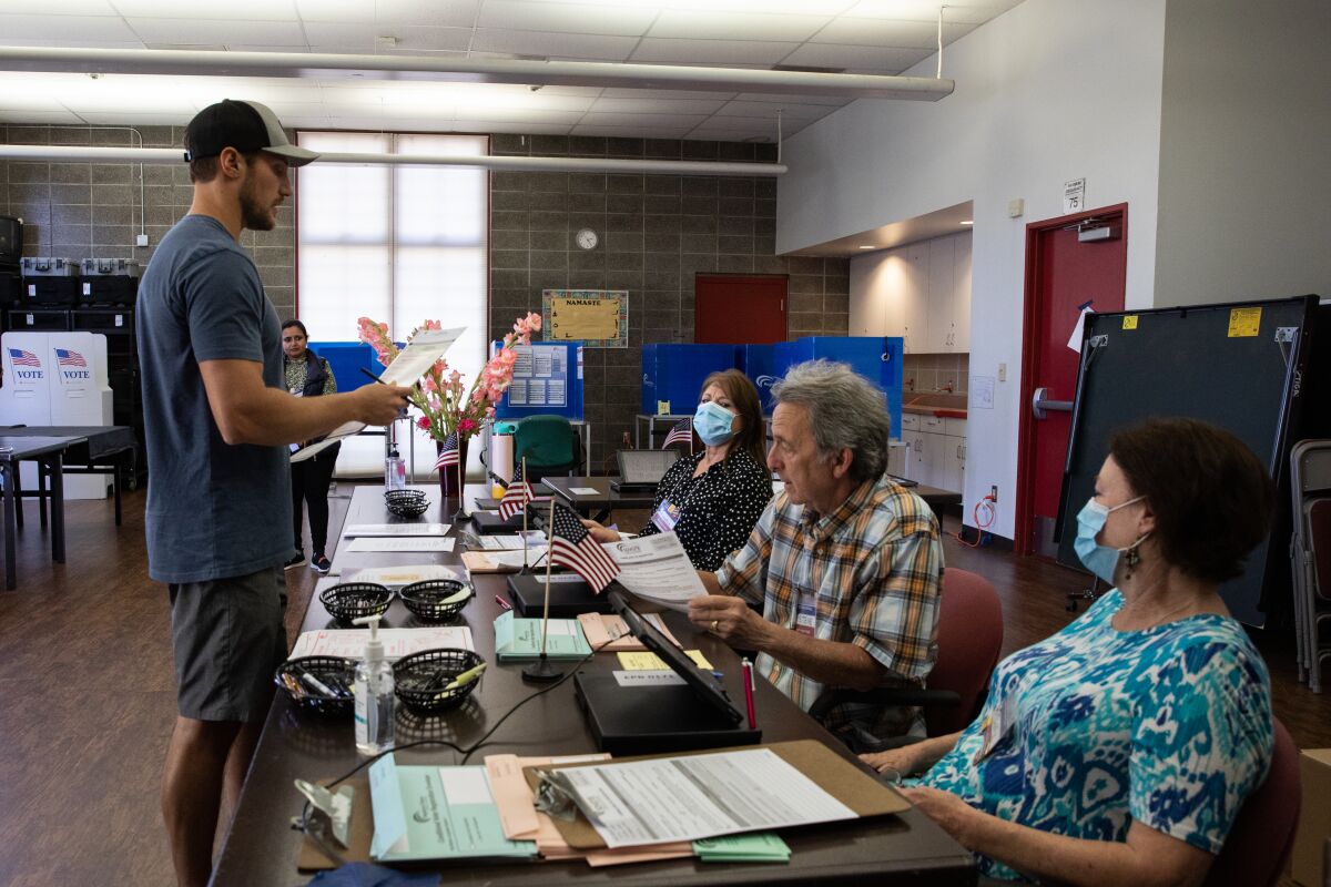 Poll workers help John Schneider check in at a vote center in Carmel Mountain Ranch Community Park in Poway