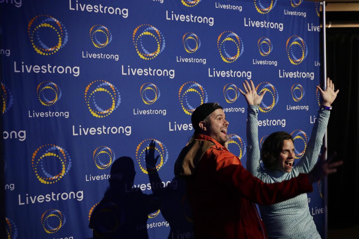 In this Monday, Feb. 3, 2020 photo, guest pose with a new logo for Livestrong at an event in Austin, Texas. The Livestrong cancer charity is on a mission to reinvent itself. It has survived a dramatic fall in contributions and donations since founder Lance Armstrong's performance-enhancing drug scandal. (AP Photo/Eric Gay)