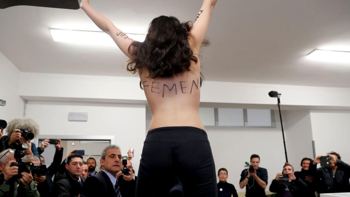 A topless Femen activist protests at a Milan polling station where former Italian Prime Minister Silvio Berlusconi was about to vote.