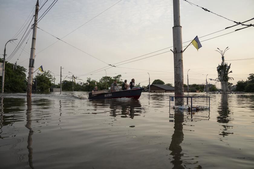 People ride by a boat through a flooded neighborhood in Kherson, Ukraine, Wednesday, June 7, 2023. Floodwaters from a collapsed dam kept rising in southern Ukraine on Wednesday, forcing hundreds of people to flee their homes in a major emergency operation that brought a dramatic new dimension to the war with Russia, now in its 16th month. (AP Photo/Evgeniy Maloletka)