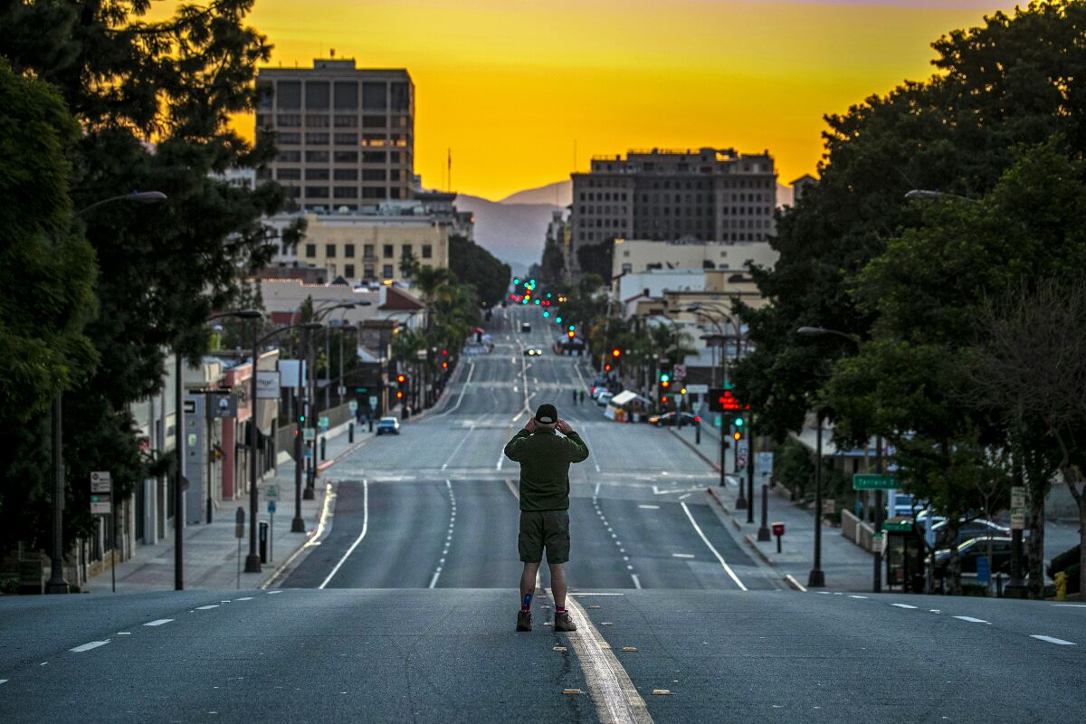 A man stands in the center of an empty four-lane city street