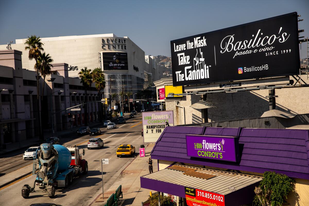 A billboard with white letters and a black background reads "Leave the mask, take the cannoli," and "Basilico's pasta e vino"