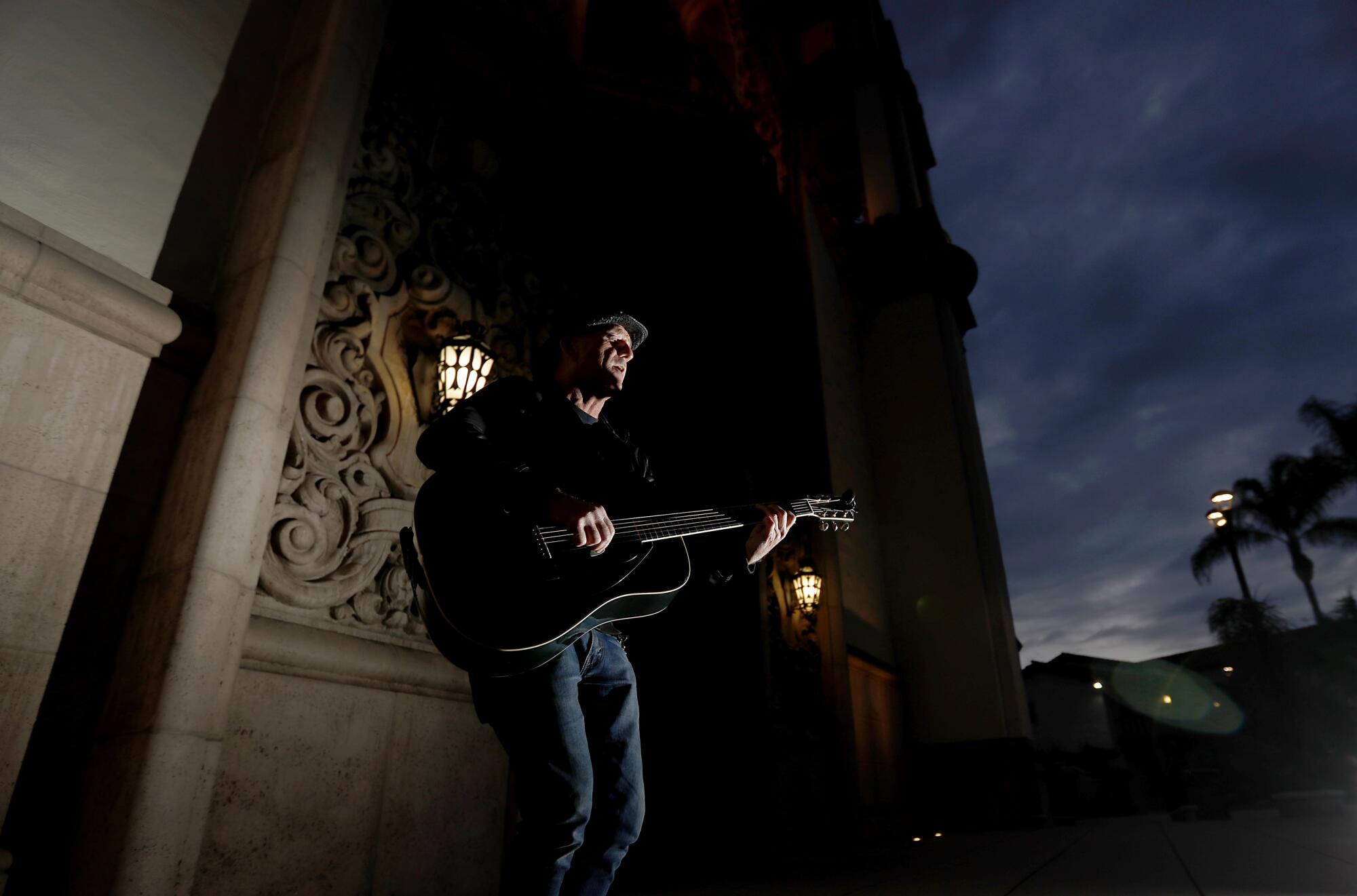 Gary Saint Germain plays guitar at dusk in front of St. Charles Borromeo Catholic Church in North Hollywood. In coronavirus lockdown with two roommates, Saint Germain, 58, recently started playing and singing outside the church to get fresh air and relieve boredom.
