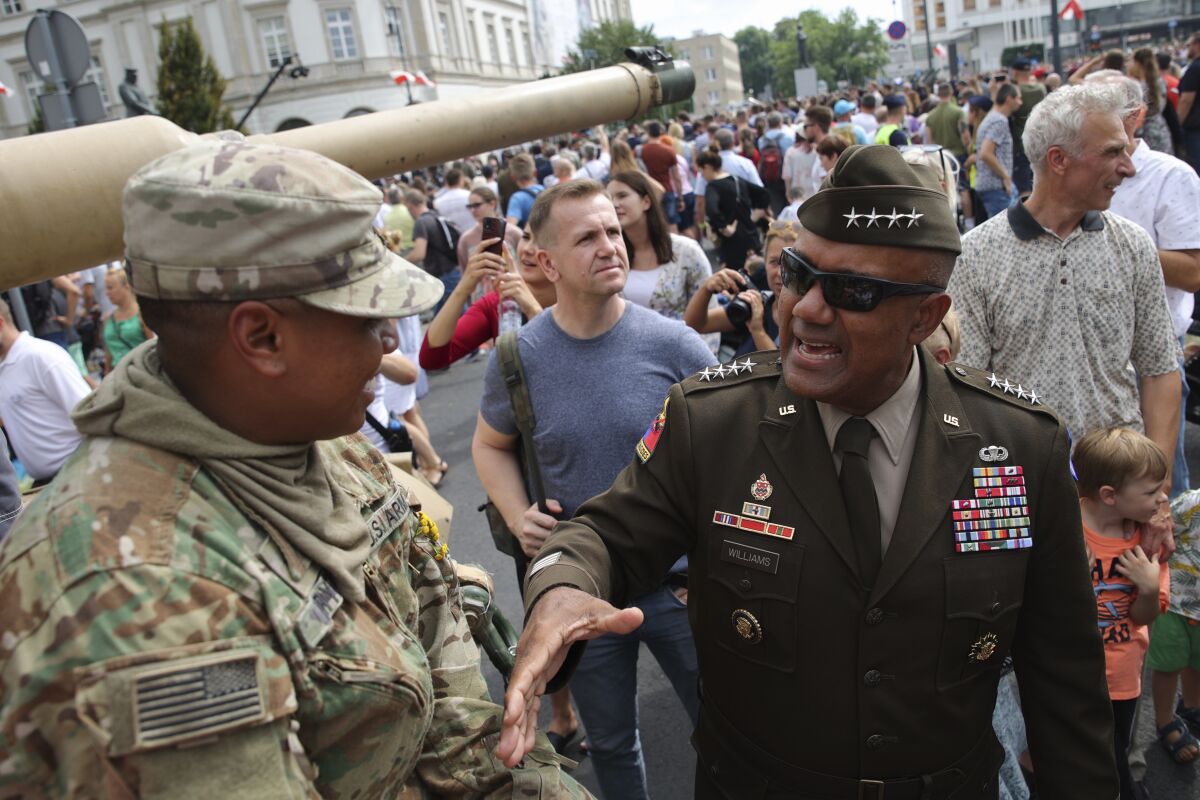 Gen. Darryl Williams, the new commanding general of United States Army Europe and Africa, second right, greets with US soldier during a picnic marking the Polish Army Day in Warsaw, Poland, Monday, Aug. 15, 2022. The Polish president and other officials marked their nation's Armed Forces Day holiday Monday alongside the U.S. army commander in Europe and regular American troops, a symbolic underlining of NATO support for members on the eastern front as Russia wages war nearby in Ukraine. (AP Photo/Michal Dyjuk)