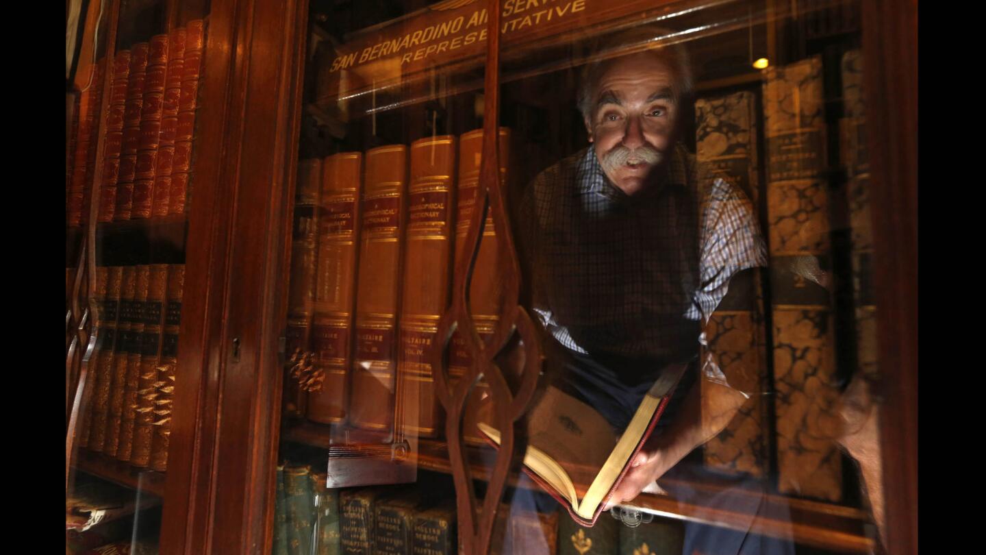 Leonard Bernstein, the second-generation owner of Caravan Book Store in downtown Los Angeles, is reflected in the glass door of one of his many antique book cases. His parents opened the shop in 1954.