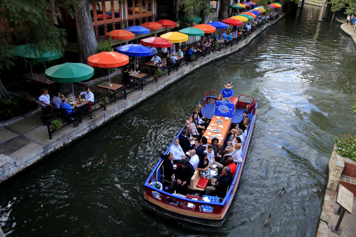 One of the Rio Taxi dinner/cocktail cruise charters floats past the colorful umbrellas at Casa Rio Restaurant on the San Antonio River along the river walk in San Antonio.