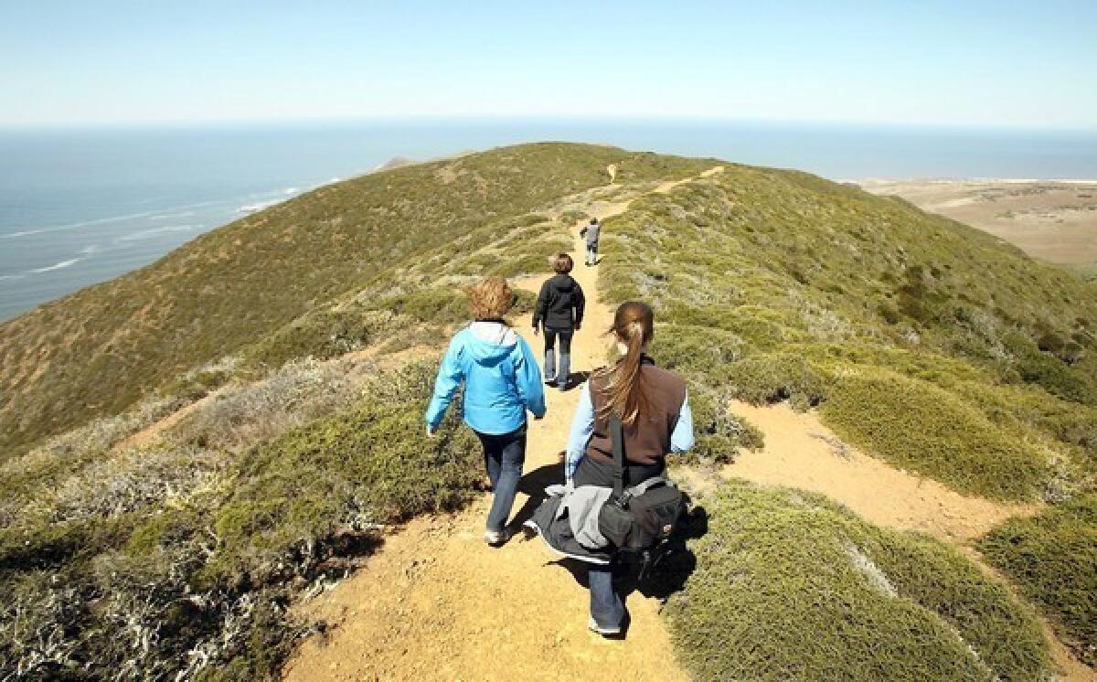 Representatives of the Land Conservancy of San Luis Obispo County and the military hike the northern boundary of Vandenberg Air Force Base to view land recently acquired under an agreement that will protect it from development.