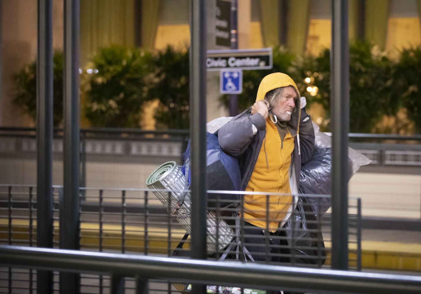 A homeless man, carrying bags full of cans, walks along C Street before sunrise near San Diego City Hall, January 23, 2020 during the annual point-in-time homeless count.