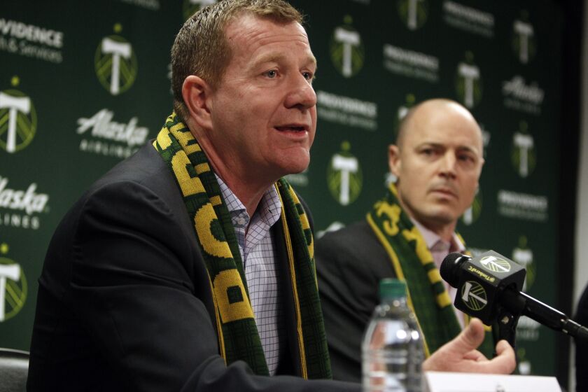 FILE - Portland Timbers team president and general manager Gavin Wilkinson, left, speaks as team owner Merritt Paulson, right, listens during an MLS soccer news conference on Jan. 8, 2018, in Portland, Ore. Wilkinson and Paulson have been removed from any decision-making roles with the Portland Thorn's National Women’s Soccer League club until the findings are released from an ongoing investigation into numerous scandals around the league. (Sean Meagher/The Oregonian via AP)