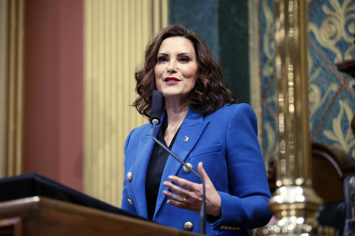 A woman in a blue blazer speaking at a lectern 