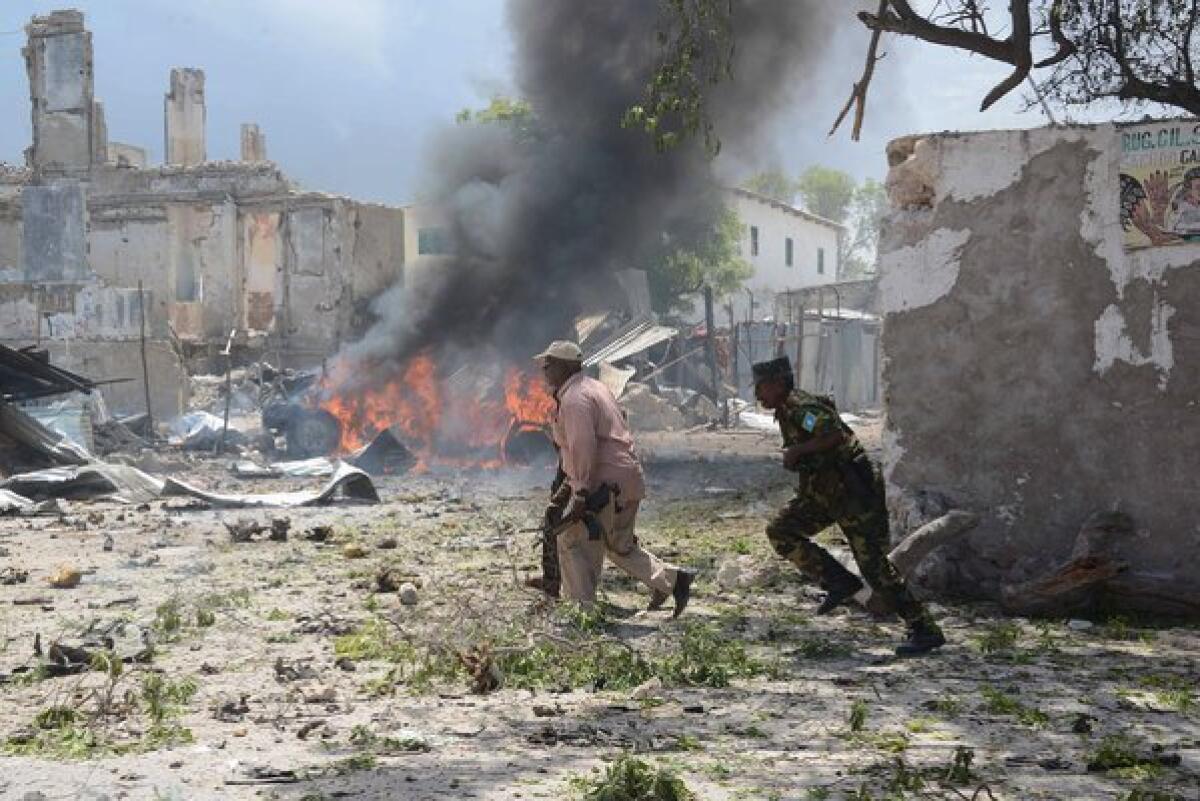 Somali police run for cover Sunday after gunmen wearing suicide vests stormed the main court complex in Mogadishu and took hostages.