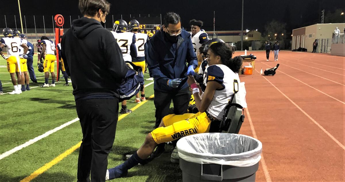 Trainers and coaches bend over an injured football player