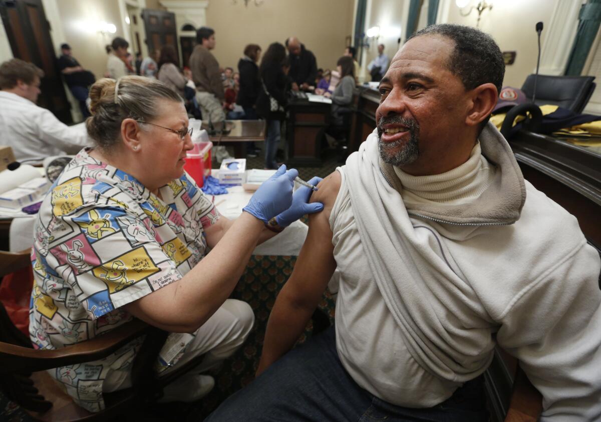 Claude Flanagan receives a flu shot from Geneva Hill, a licensed vocational nurse, during a free flu vaccine clinic this week in Sacramento. This season's outbreak, though still strong, appears to be waning, the CDC says.