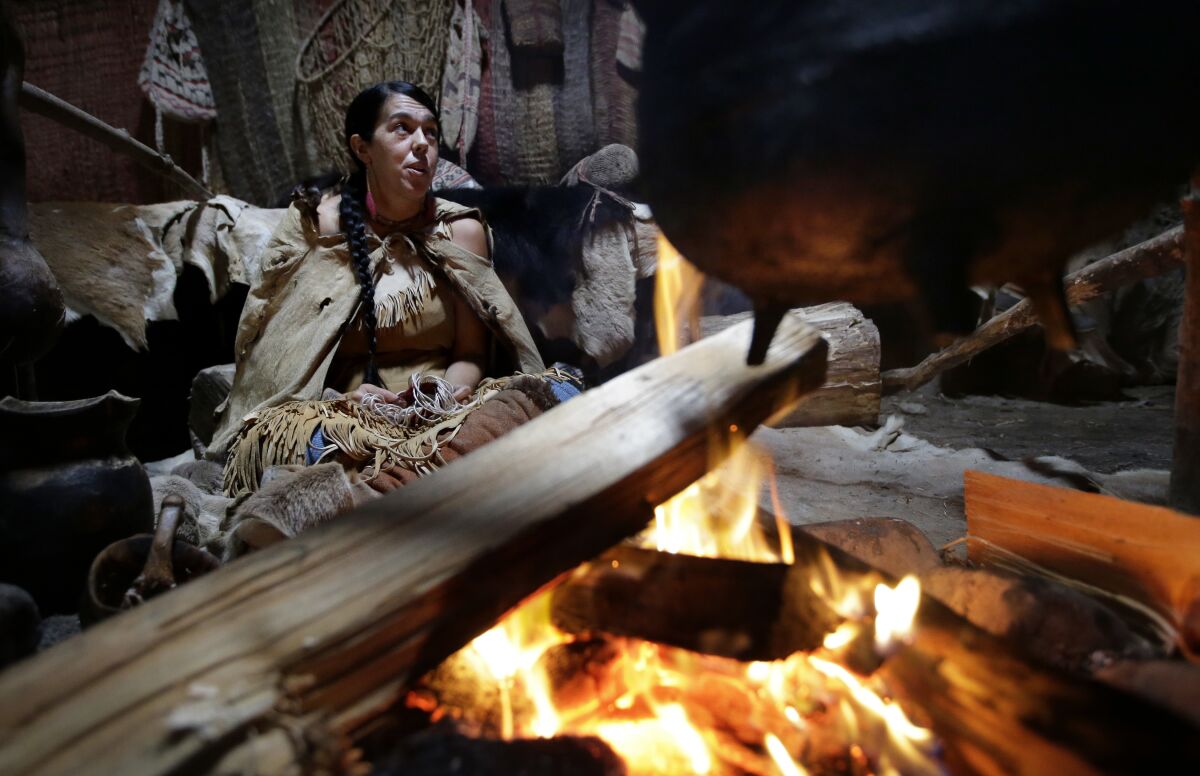 Mashpee Wampanoag Kerri Helme, of Fairhaven, Mass., uses plant fiber to weave a basket while sitting next to a fire on November 15, 2018, at the Wampanoag Homesite at the Plimoth Patuxet Museums, in Plymouth, Mass. Native Americans in Massachusetts are calling for a boycott of a popular living history museum featuring colonial reenactors portraying life in Plymouth, the famous English settlement founded by Pilgrims arriving on the Mayflower. They say the Plimoth Patuxet museum hasn't lived up to its mandate to create a "bi-cultural museum" telling equally the stories of the European and indigenous communities. (AP Photo/Steven Senne, File)
