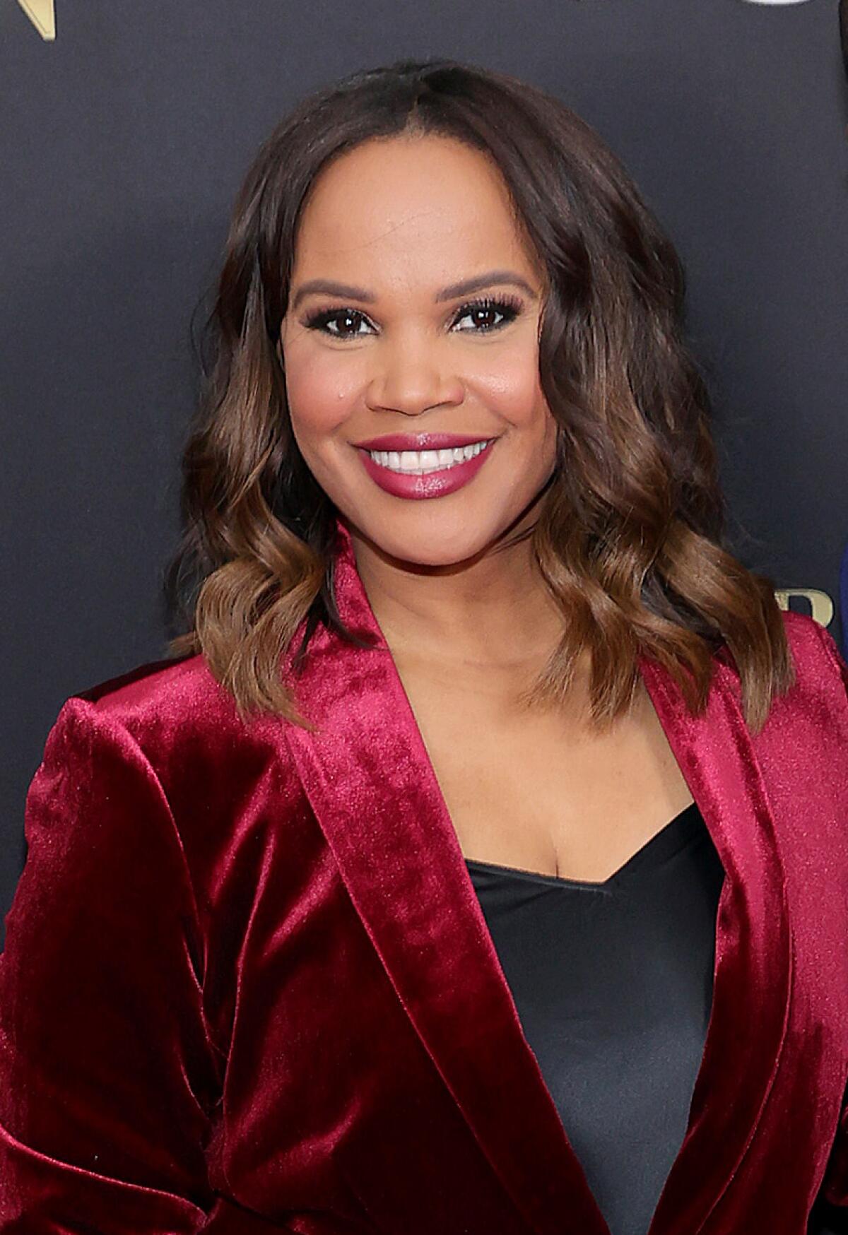 A woman posing in a red velvet suit.