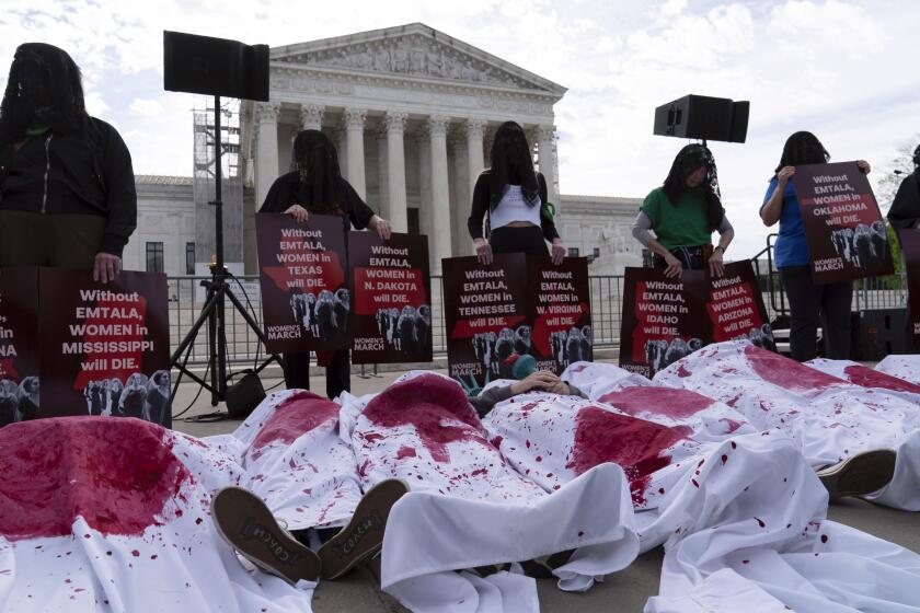 Abortion rights activists, covered in blankets with red paint, lie down as they rally outside the Supreme Court, Wednesday, April 24, 2024, in Washington. (AP Photo/Jose Luis Magana)