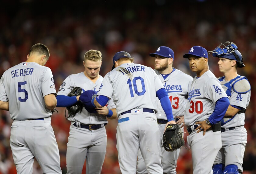 Dodgers players stand near the mound during a pitching change.