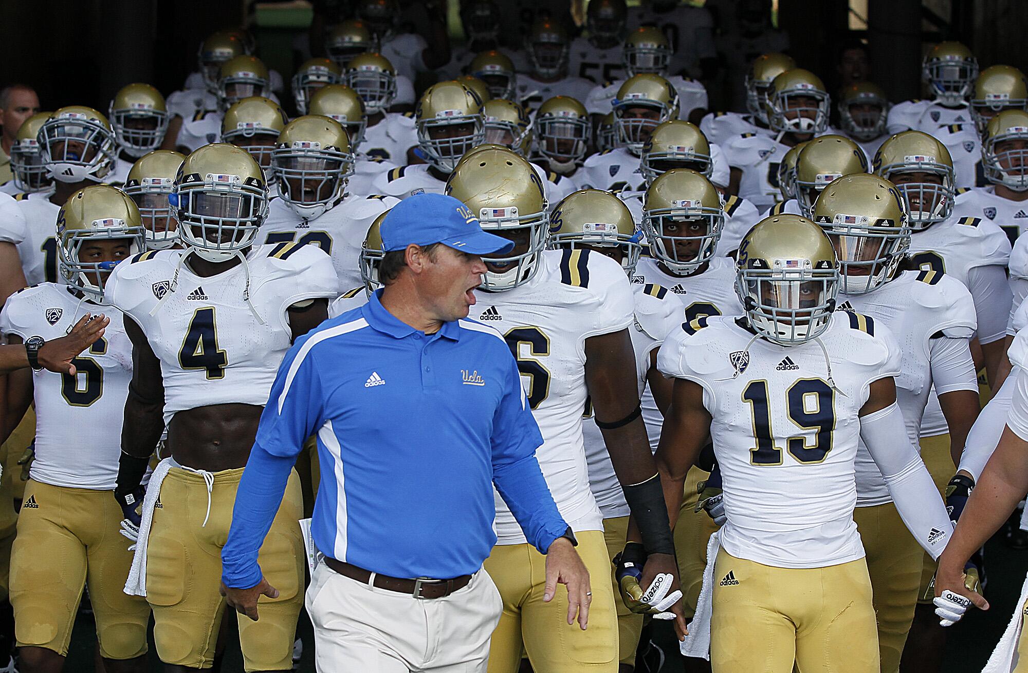 Coach Jim Mora Jr. leads the UCLA Bruins to the field to take on the Rice Owls at Rice Stadium in 2012.