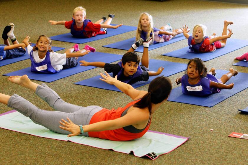 Yoga teacher Jackie Bergeron works with students at Paul Ecke Central Elementary School in Encinitas. Students attend two 40-minute yoga classes each week.
