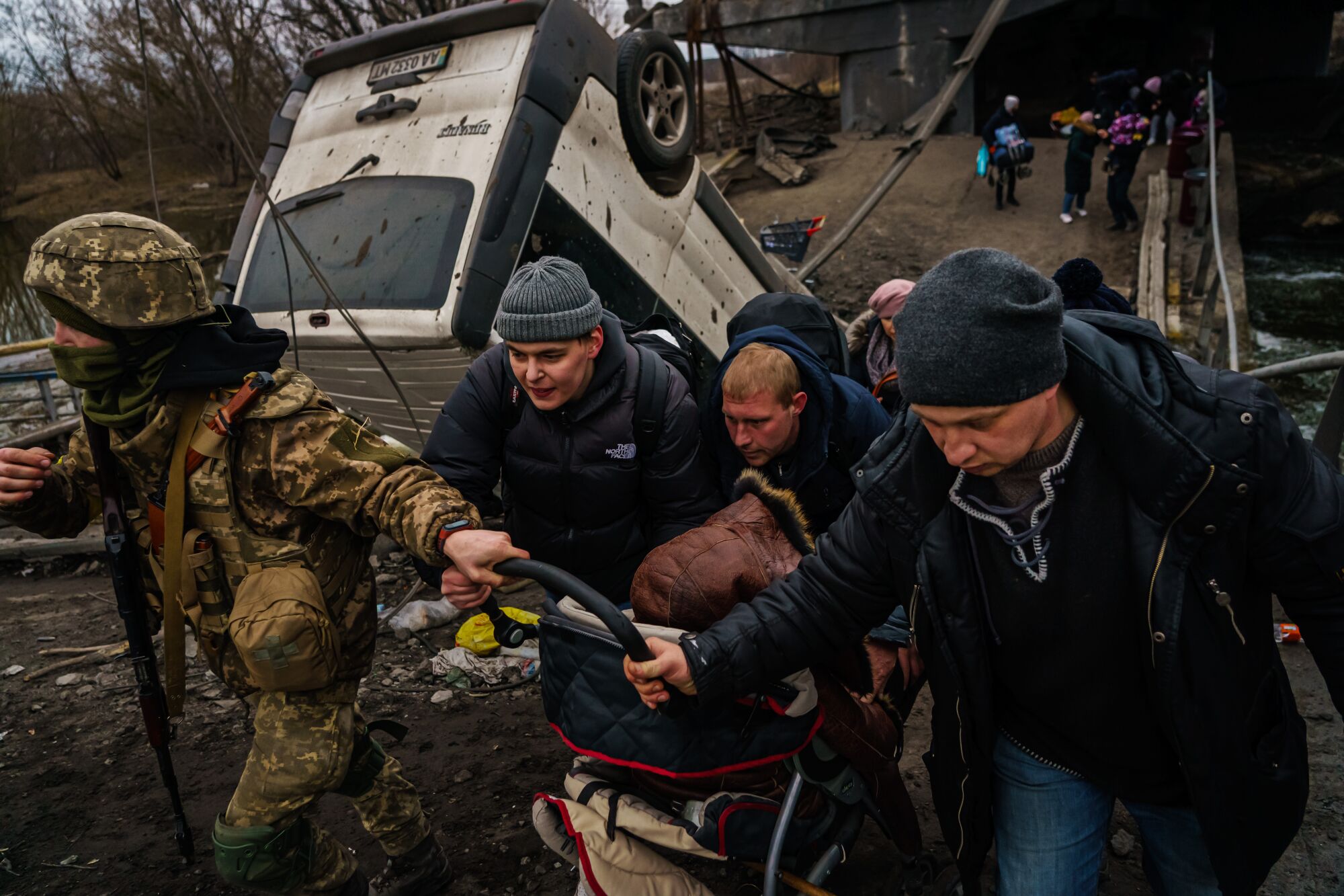 Local residents cross the Irpin River as they evacuate Irpin, outside Kyiv.