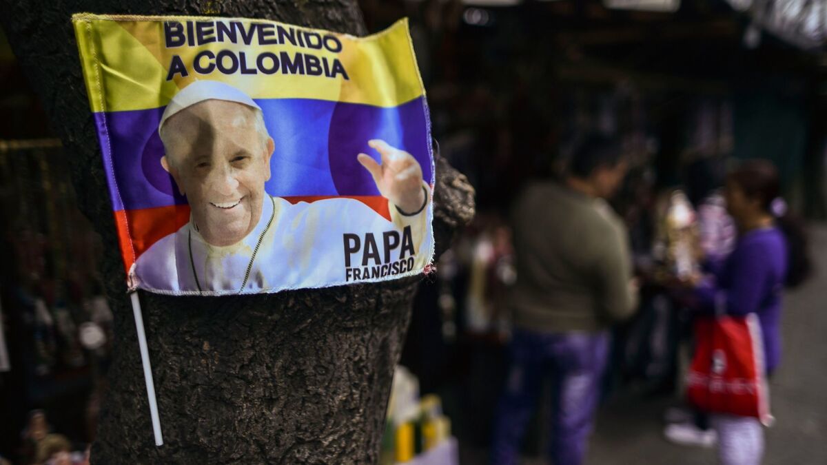 Pope Francis, who is to arrive in Colombia on Wednesday, is seen on a flag in Bogota.