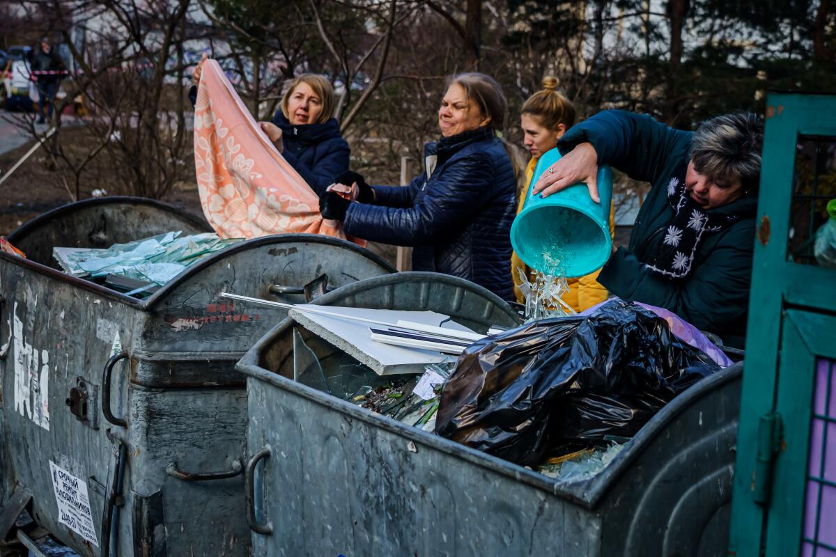 People empty broken glass into trash containers in Kyiv