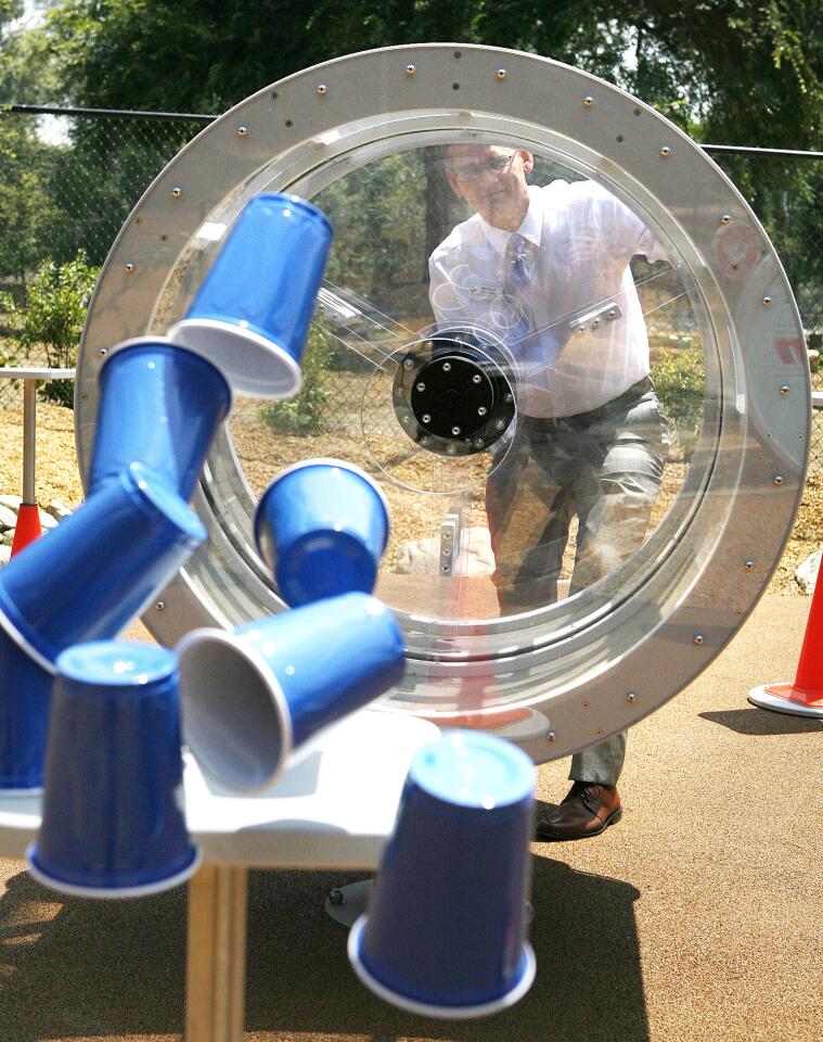 Michael Shanklin, the CEO of Kidspace Children's Museum pushes a large plunger which sends a pulse of air to knock down a stack of cups in the Enchanted Physics Forest.