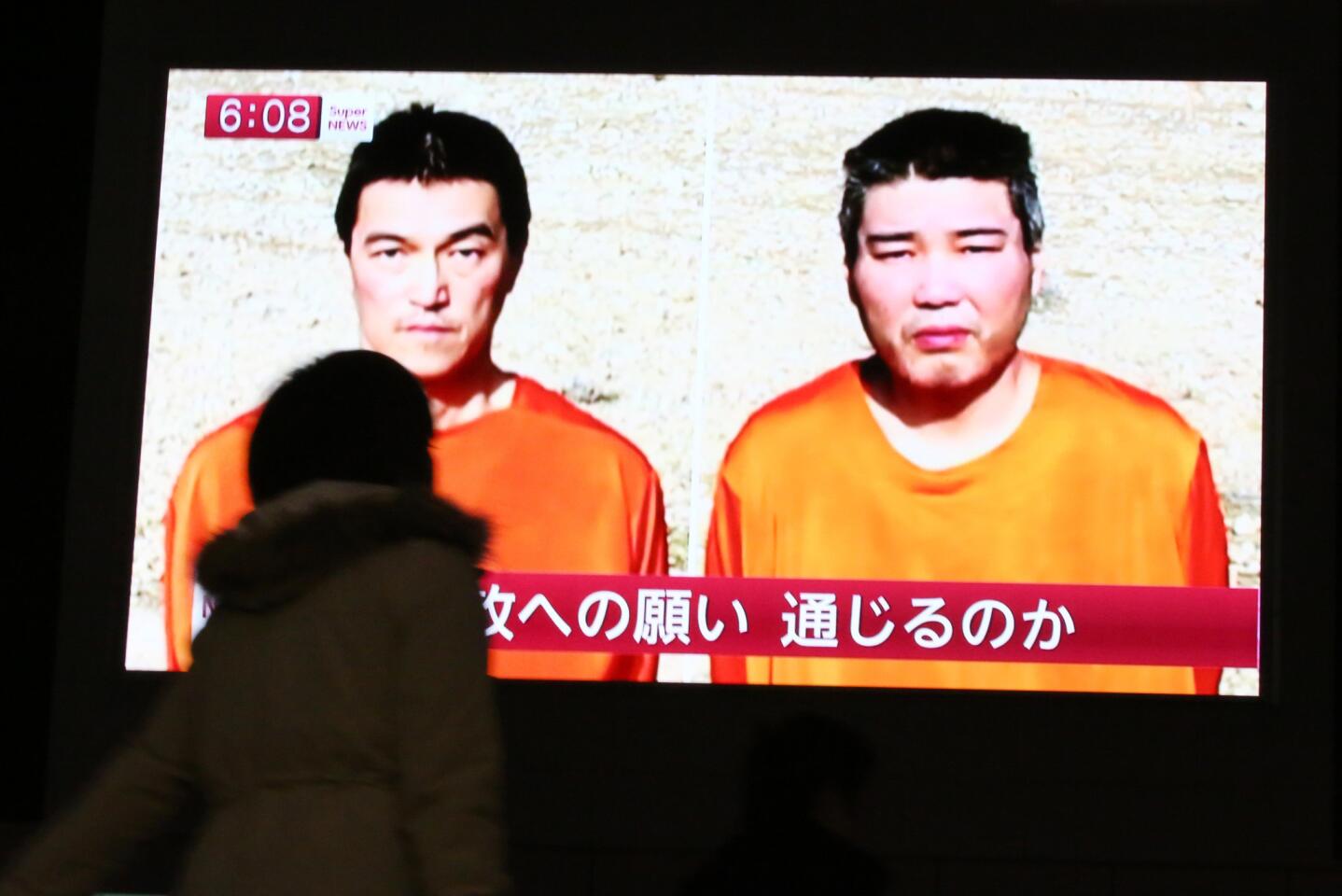 A Tokyo passerby watches a Jan 23 TV news program reporting on two Japanese hostages, Kenji Goto, left, and Haruna Yukawa, held by Islamic State.