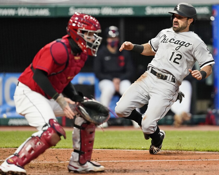 Chicago White Sox's Adam Eaton, right, scores as Cleveland Indians' Roberto Perez, left, waits for the ball in the sixth inning in a baseball game, Tuesday, April 20, 2021, in Cleveland. (AP Photo/Tony Dejak)