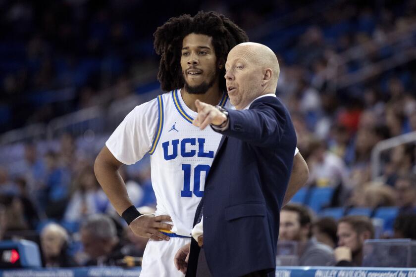 UCLA coach Mick Cronin talks with guard Tyger Campbell during a game