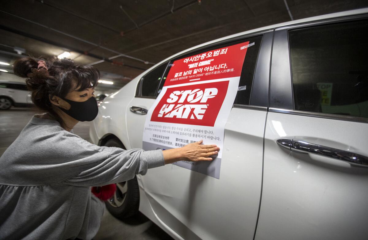 Heidie Lee places a "Stop hate" sign on her car before start of a car caravan.