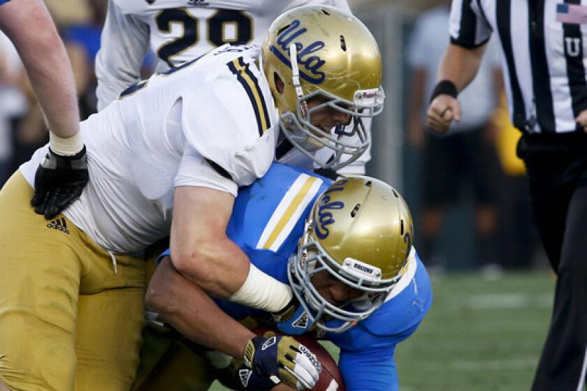 UCLA's Aaron Porter tackles running back James Jordon during a 2013 spring practice session. Porter, who moved from linebacker to running back last fall, is not presently enrolled at the university.