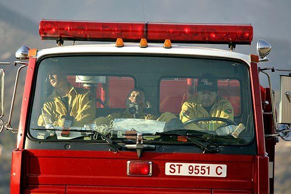 Three members of a state fire crew take a rest in their firetruck along Soledad Canyon Road in Acton this morning. The Station fire marched north overnight through remote mountain ridges toward Acton, forcing mandatory evacuations.