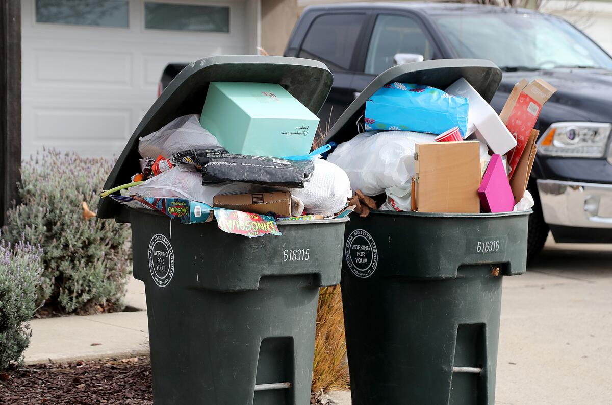 Trash cans overflow with garbage on Tuesday along Columbia Drive in Costa Mesa.