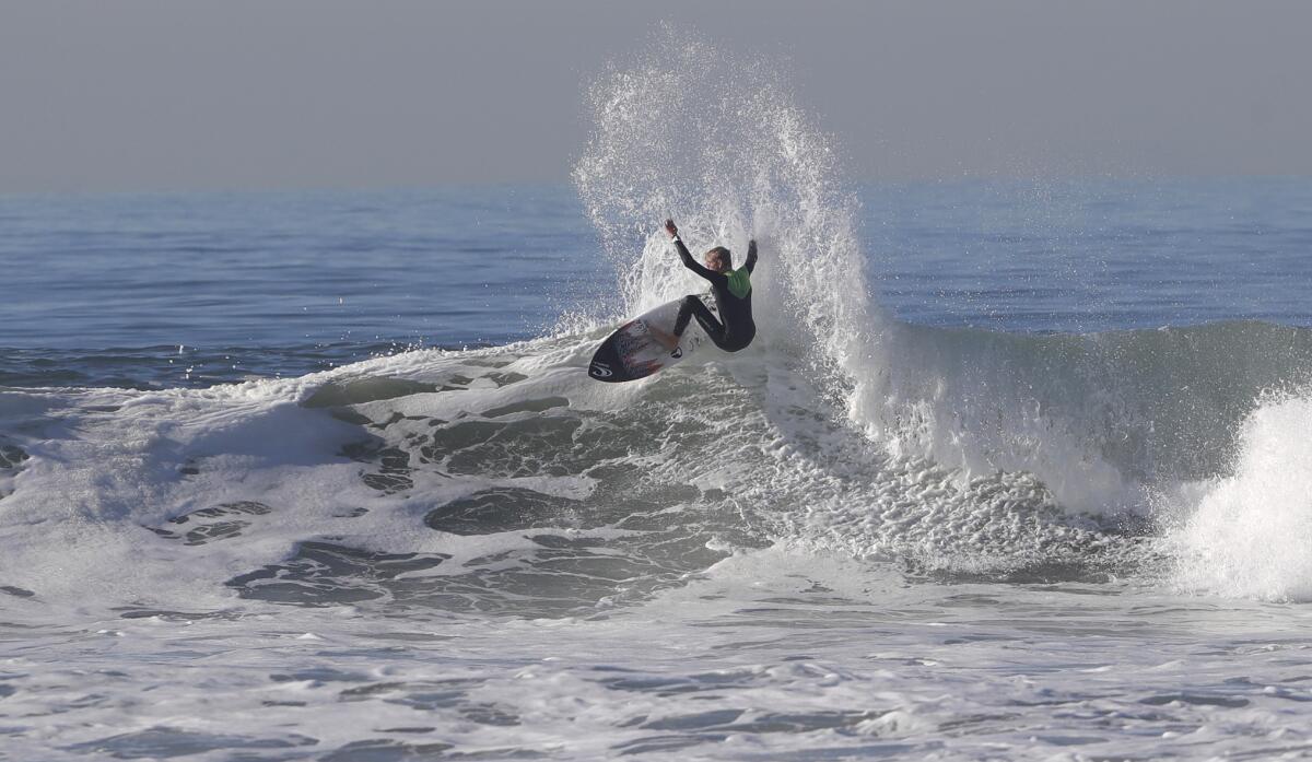 A member of the boys' USA Surfing junior team goes off the top of a wave.