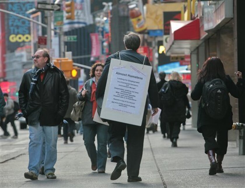 Paul Nawrocki, from Beacon, N.Y., wears a sign as he walks through Times Square seeking employment, New York, Tuesday Nov. 18, 2008. The government says new claims for unemployment benefits jumped last week to a 16-year high, providing more evidence of a rapidly weakening labor market. (AP Photo/Bebeto Matthews)