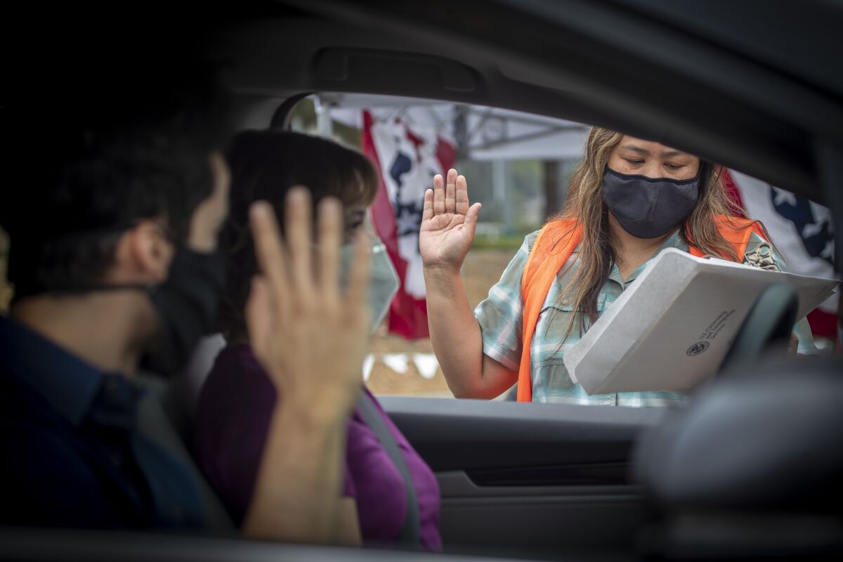 Rochelle Reyes administers oath to Brian Gebel, 26, as his mom, Liliana, listens during a drive-through ceremony.