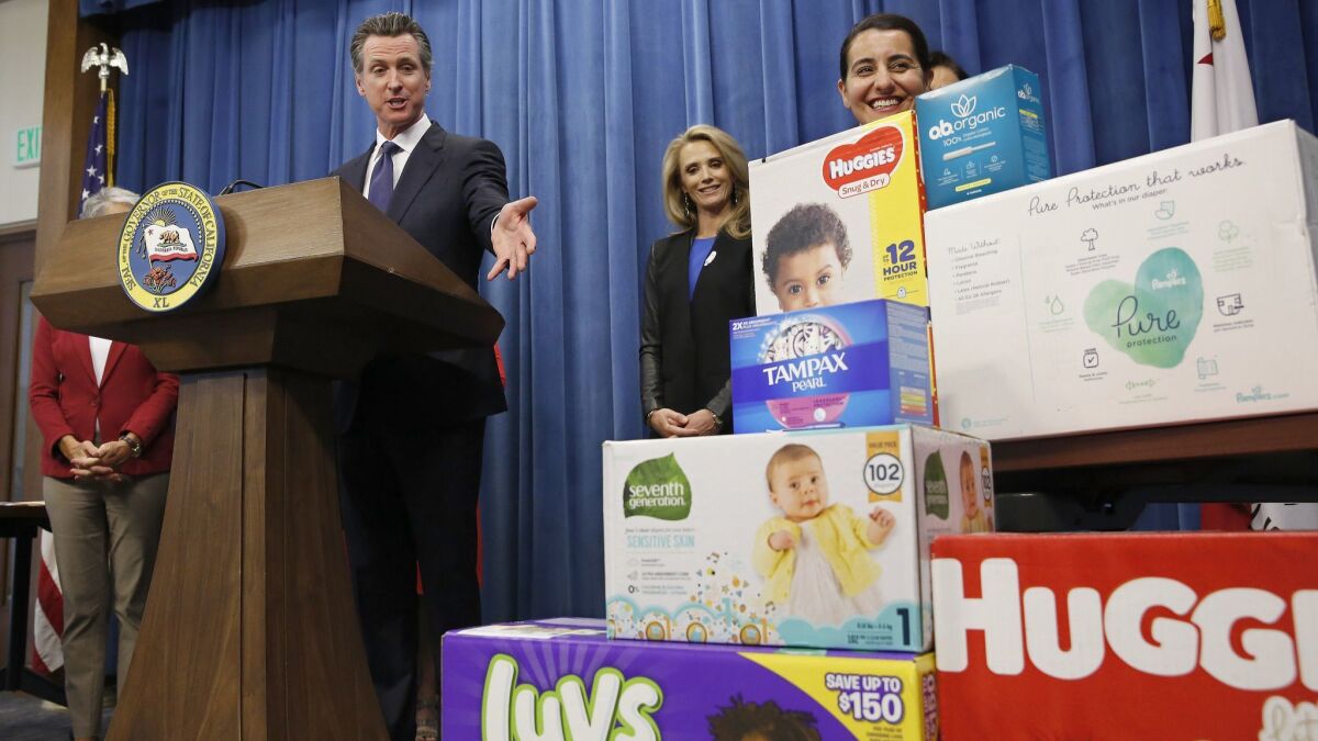 Gov. Gavin Newsom gestures towards boxes of tampons and diapers after proposing to eliminate state sales tax on such products in his upcoming state budget during a news conference in Sacramento, Calif. on May 7.