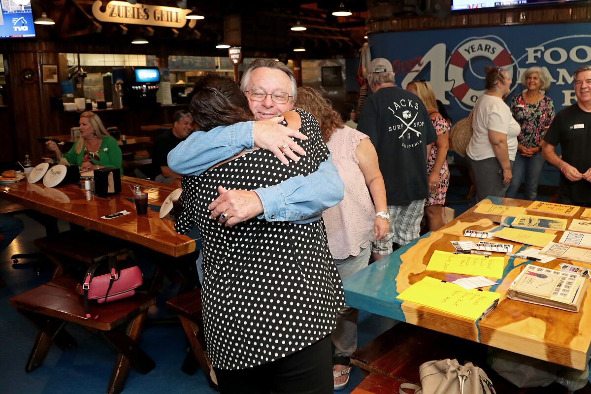 Neil Swaigler, center, a former teacher, shares a hug with Yolanda Johnson during Bushard Elementary School's reunion.