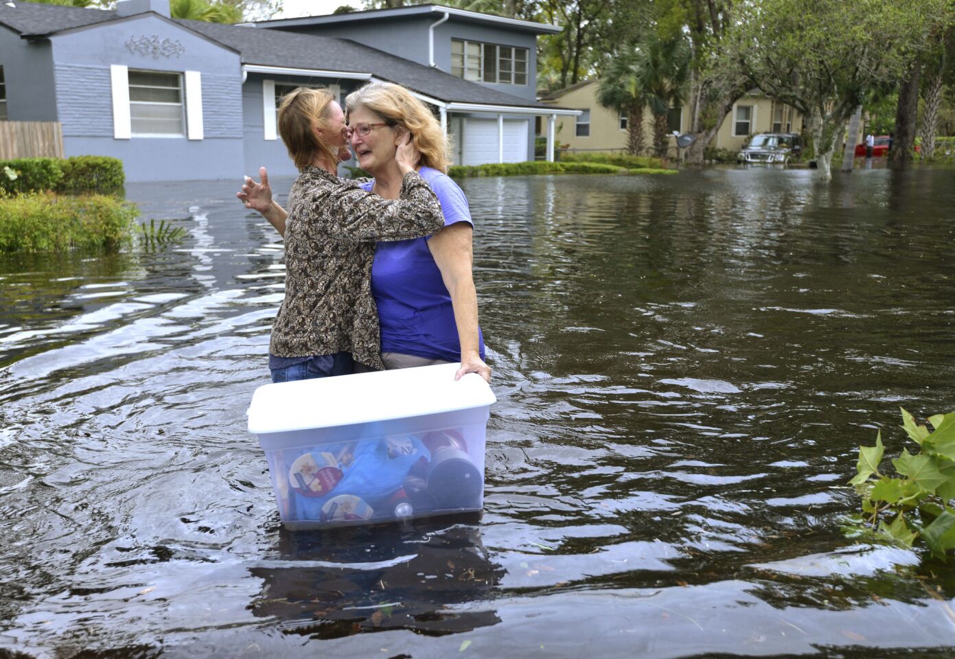 Charlotte Glaze, left gives Donna Lamb a hug as she floats out some of her belongings in floodwaters in Jacksonville,.