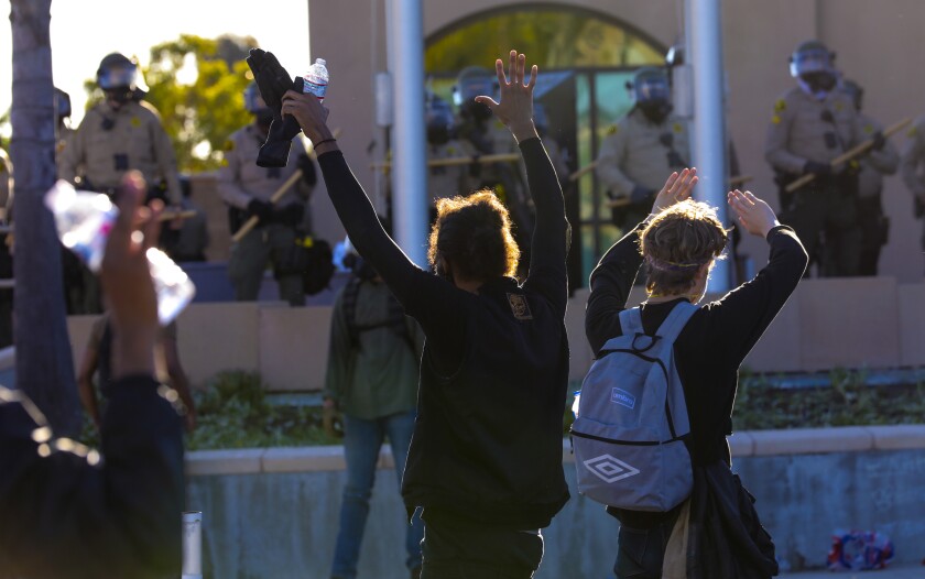 Protestors hold their hands up outside the La Mesa Police Department during a demonstration May 30, 2020.