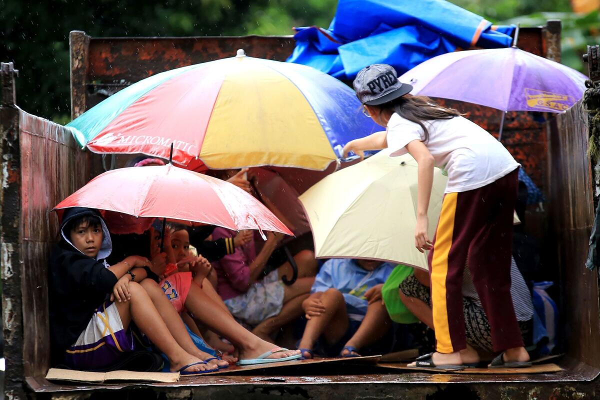 Young residents sit in a truck after the local government implemented preemptive evacuations at Barangay Matnog, Daraga, Albay province on Sunday due to the approaching Typhoon Nock-Ten.