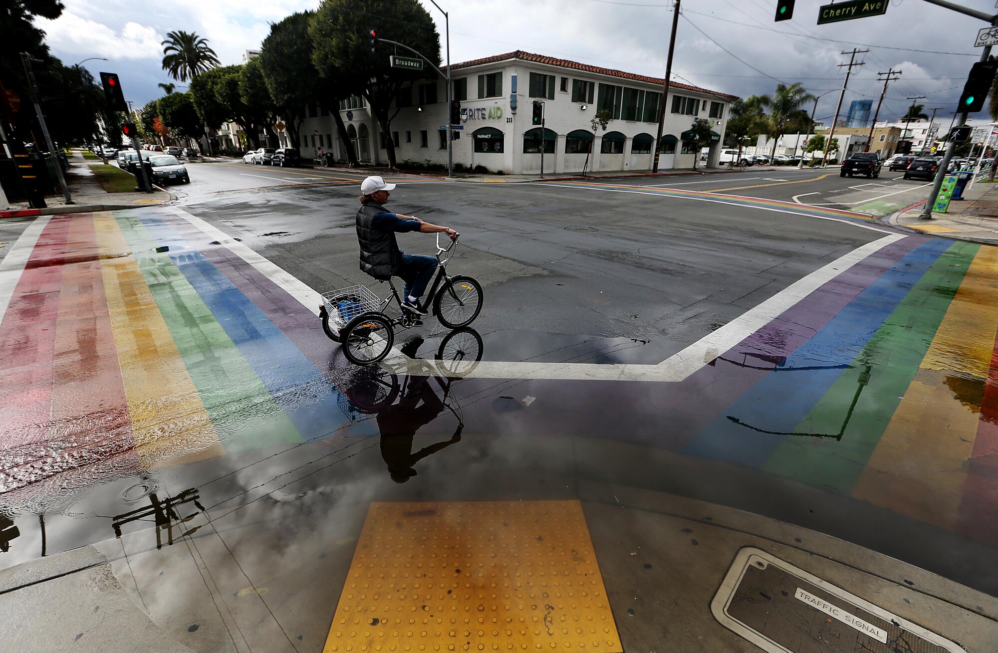 A cyclist rides past a rain puddle at the intersection of Cherry Avenue and Broadway in Long Beach. 