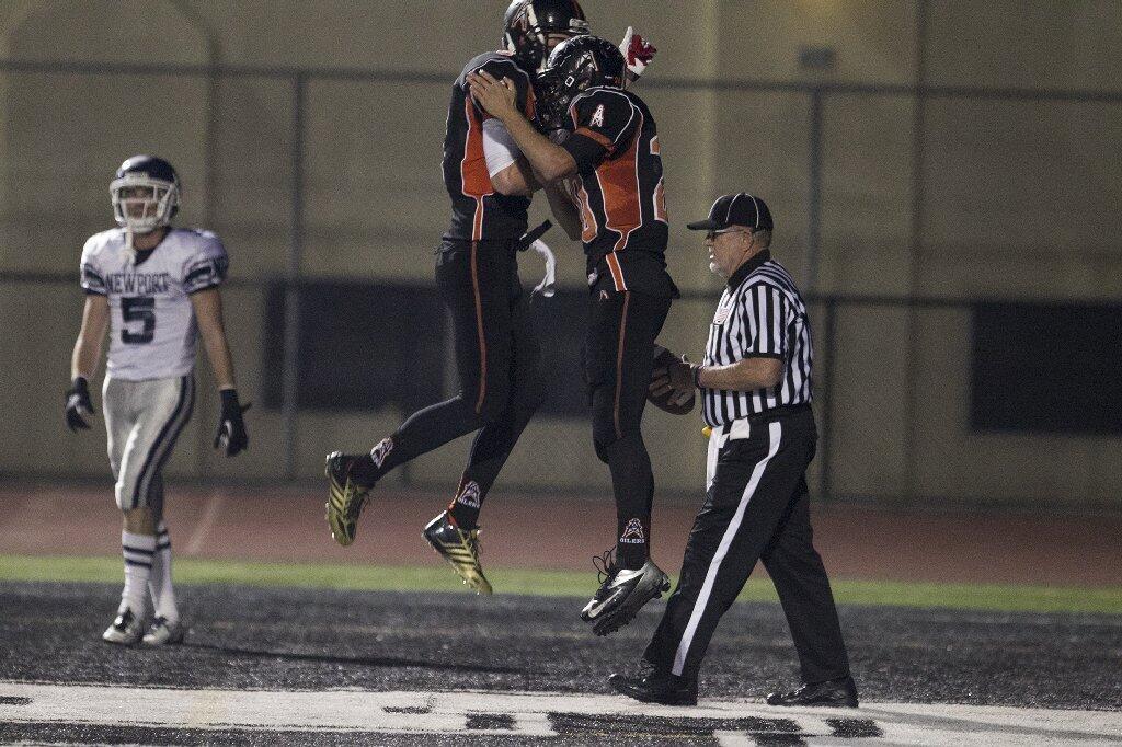 Huntington Beach's Nolan Thompson, left, celebrates with Hunter Simmons after he scored a touchdown against Newport Harbor during a game on Friday.