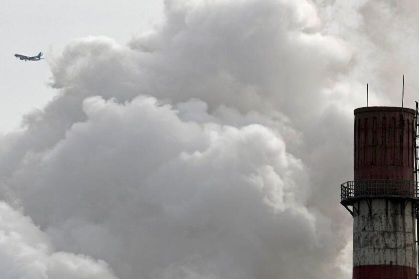 FILE - In this Feb. 28, 2017 file photo, a passenger airplane flies behind steam and white smoke emitted from a coal-fired power plant in Beijing. On Monday, Nov. 13, 2017, scientists projected that global carbon pollution has risen in 2017 after three straight years when the heat-trapping gas didnâ€™t go up at all. (AP Photo/Andy Wong, File)