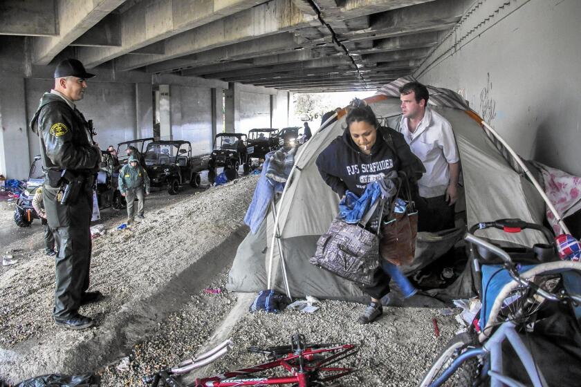 Sheriff’s Deputy Michael Galvan, left, warns a couple living under the 5 Freeway near the San Gabriel River in Pico Rivera about the dangers of flooding.