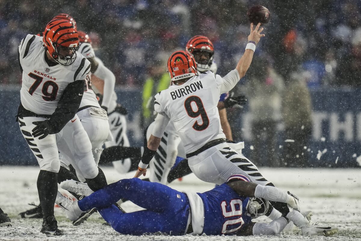 Cincinnati Bengals quarterback Joe Burrow (9) passes while taking a hit from Buffalo Bills defensive end Shaq Lawson (90) during the third quarter of an NFL division round football game, Sunday, Jan. 22, 2023, in Orchard Park, N.Y. (AP Photo/Seth Wenig)