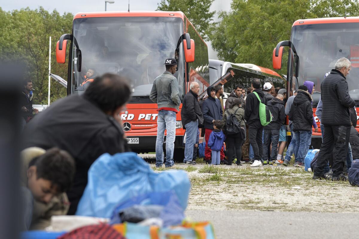 Migrants from Syria, Afghanistan and Iraq wait to board buses to other German cities outside a refugee accomodation facility in Munich on September 7.