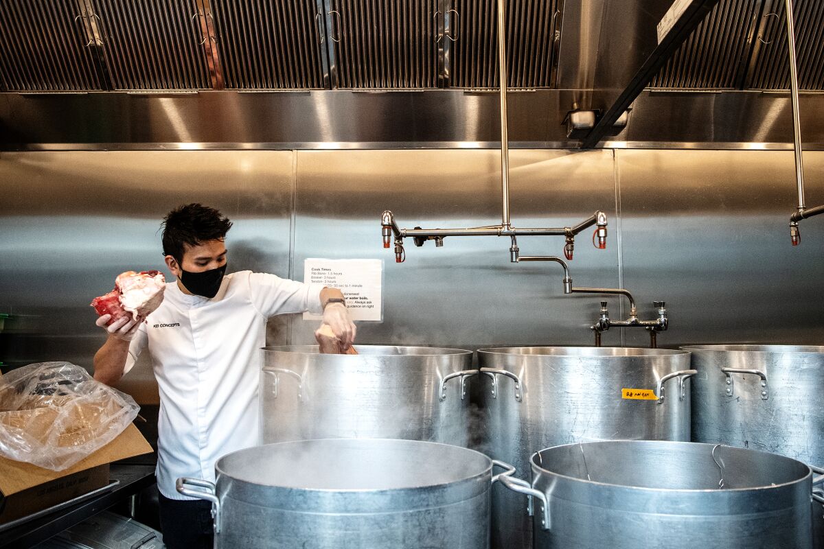 Chef Viet Nguyen, owner of Súp Noodle Bar, add cuts of meat to a pot to begin cooking the broth for his pho.
